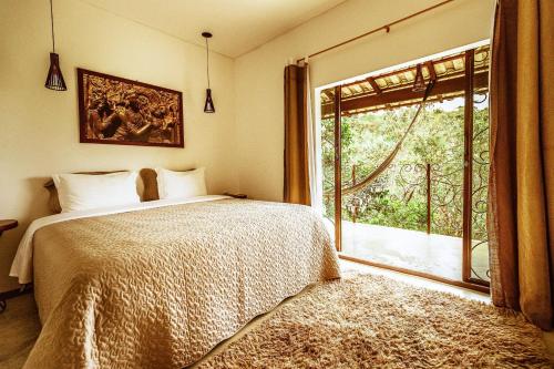 a bedroom with a bed and a large window at Pousada Casa de Shiva in Alto Paraíso de Goiás