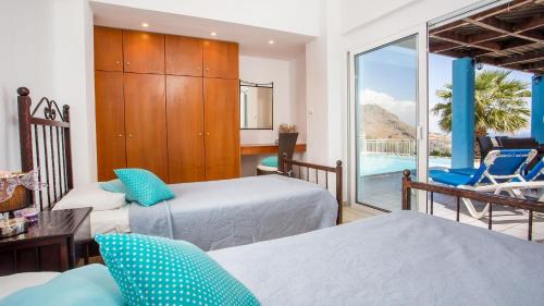 a bedroom with two beds and a balcony with a pool at Villa Selene in Archangelos