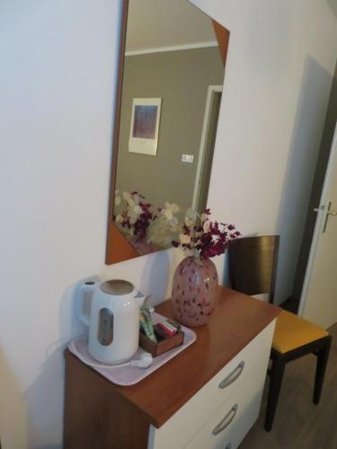 a table with a mirror and a vase of flowers on it at Guesthouse ob Sotočju Budič in Brežice