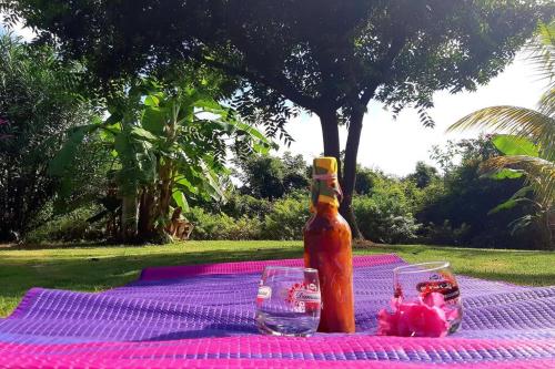 a table with a bottle of sauce and glasses on it at TI COIN RELAX bungalow vue mer piscine privée in Saint-François