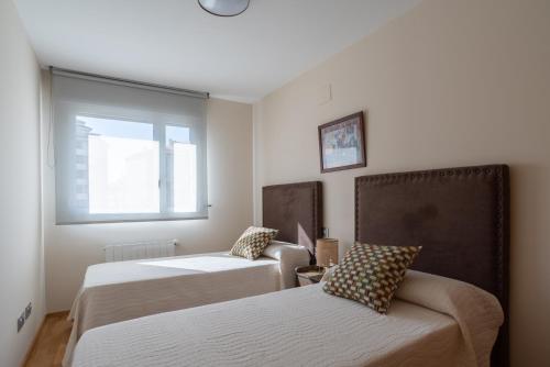 Habitación con 2 camas, sofá y ventana en Apartamento Bulevar 2 con parking gratuito, en Castellón de la Plana