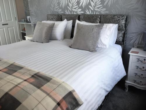 1 dormitorio con 1 cama con sábanas y almohadas blancas en Loggans Lodge en Hayle