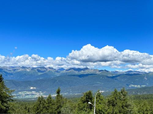 a view of a mountain range with a blue sky and clouds at PanoramaHotel Penegal in Mendola