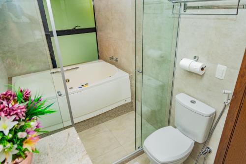 a bathroom with a toilet and a glass shower at Nova Onda Hotel in Cabo Frio