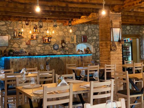 a restaurant with wooden tables and chairs and a stone wall at Alpinehouse in Theth