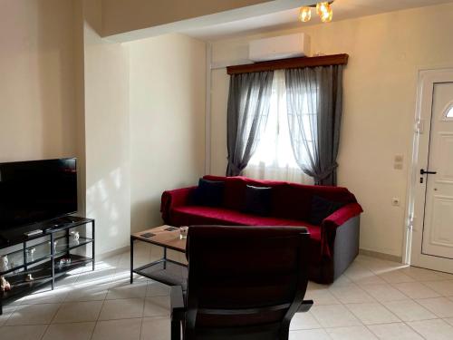 sala de estar con sofá rojo y ventana en Casa Blanca II en Pyrgos Dirou