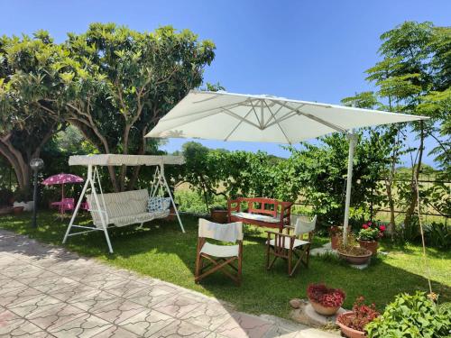 a white umbrella in a yard with chairs and a swing at Gullo Capo Vaticano in Ricadi