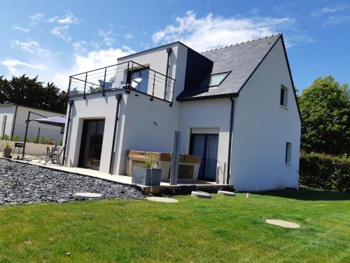 une maison blanche avec un balcon sur une pelouse dans l'établissement Maison à 200m des plages avec jacuzzi, à Trégunc