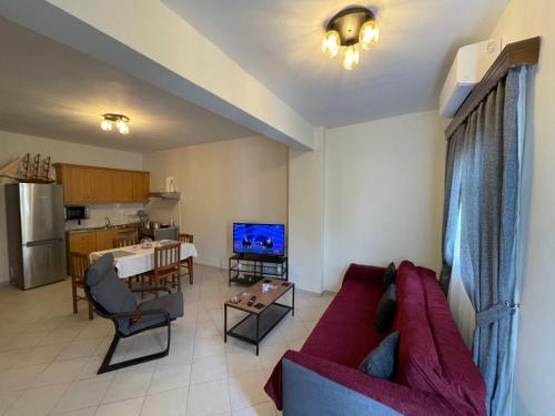 sala de estar con sofá rojo y cocina en Casa Blanca II en Pyrgos Dirou