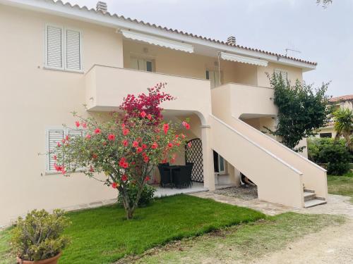 a house with a staircase and flowers in the yard at Appartamento Brezza Marina in Budoni