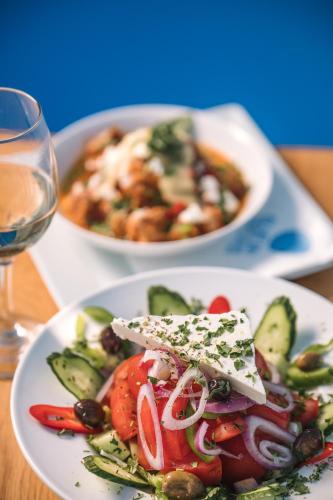 a plate of food with a salad and a glass of wine at Blue Bay Resort Village in Batsi