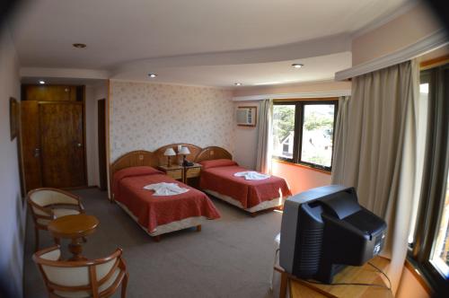 a hotel room with two beds and a television at Complejo Turístico CapArcona in Villa Gesell