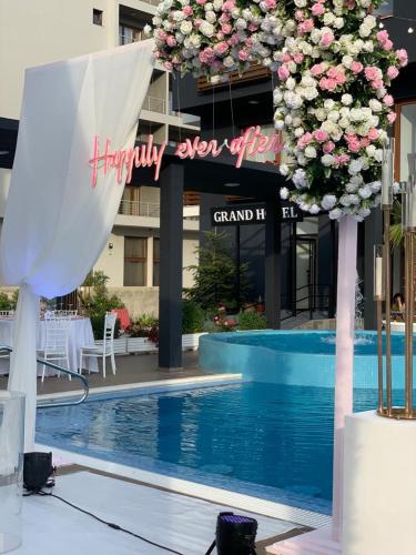a sign for a hotel with a pool and flowers at Grand Hotel Pogradec in Pogradec