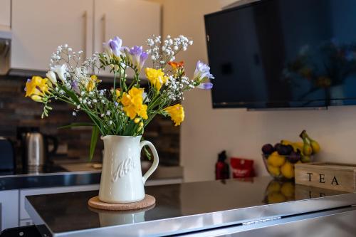 um vaso branco cheio de flores no balcão da cozinha em Eakley Stables 2 - Pogo em Newport Pagnell