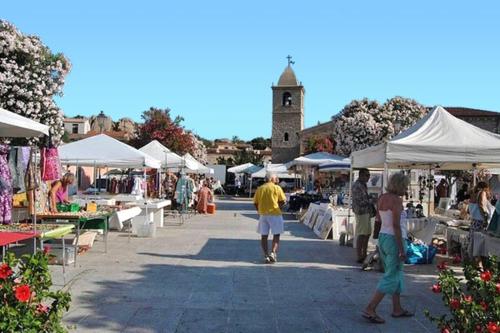 a group of people walking around a market with tents at Antica Dimora La Corona in San Pantaleo