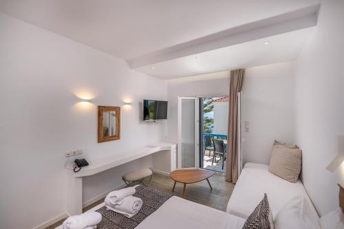 a white room with a bed and a table and a window at Blue Bay Resort Village in Batsi
