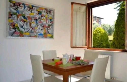 un comedor con mesa, sillas y una pintura en Home NIKY LAKE, en Desenzano del Garda