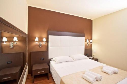 a bedroom with a large white bed with two towels at Momi's Hotel in Cavarzere