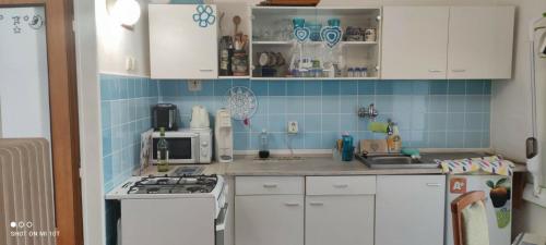 a kitchen with white cabinets and blue tiles on the wall at Apartmán Extoll in Třeboň