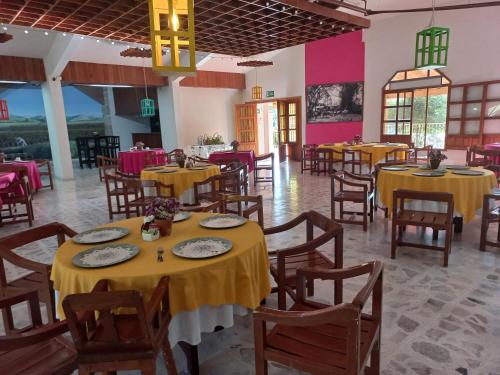 a restaurant with yellow tables and chairs and pink walls at Hotel El Molino in Río Verde
