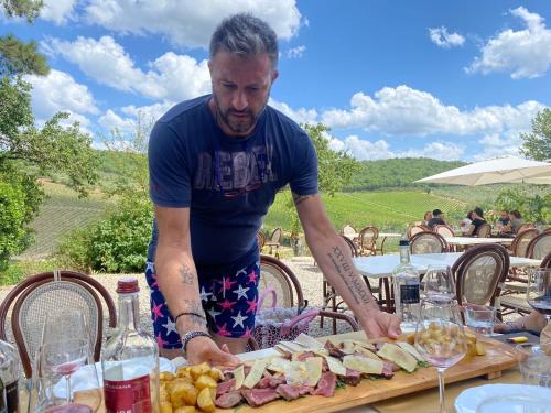 a man standing at a table with a plate of food at LOCANDA PODERE LE VIGNE in Radda in Chianti