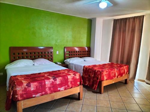 two beds in a room with green walls at Hotel Real Santa María in Cuernavaca