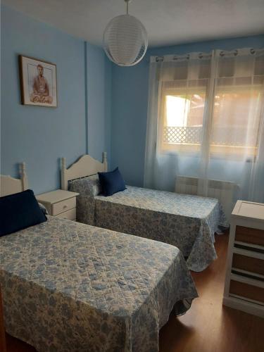 two beds in a room with blue walls and a window at La cabaña in Las Navas del Marqués