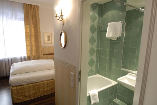a bathroom with a green tiled shower and a bed at Hotel Deutscher Kaiser in Nuremberg