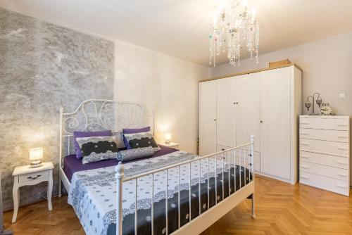 斯普利特的住宿－Artistic chill art apartment 2+2.Centar of Split.，一间卧室配有一张带紫色床单和吊灯的床。