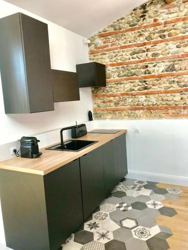 - une cuisine avec un évier et un mur en briques dans l'établissement ☆☆☆☆ SOUS LES ETOILES ☆☆☆☆, à Toulouse