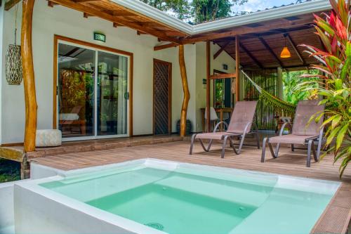 einen Pool auf einer Terrasse mit Stühlen und einem Haus in der Unterkunft La Rana De Cahuita in Cahuita