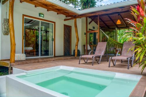 a pool on a deck with chairs and a house at La Rana De Cahuita in Cahuita