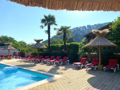 een zwembad met stoelen en parasols naast een resort bij Hameau du Prat in Ribes