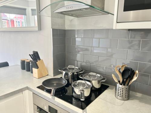 a kitchen with four pots and pans on a stove at 2 Bedroom Apartment in South Hampstead in London