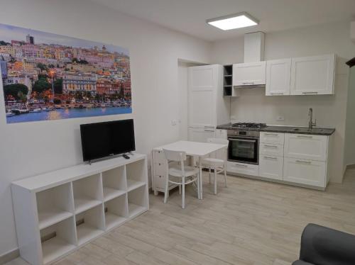 cocina con armarios blancos y mesa con TV en Apartments Villas Cagliari en Cagliari
