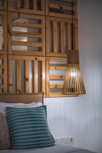 a lamp hanging over a bed with a blue pillow at Blue Bay Resort Village in Batsi