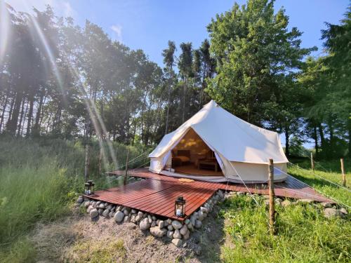 a tent on a wooden deck in a field at Under Canvas Bornholm in Østermarie
