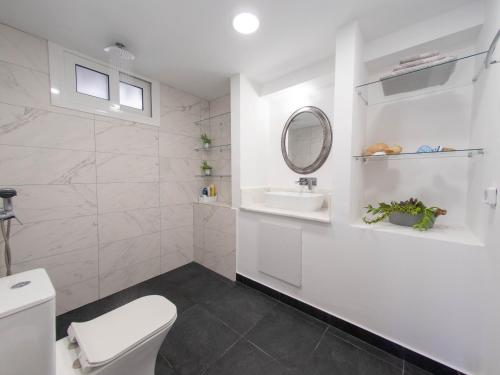 Un baño blanco con inodoro y lavabo. en Up the stairs renovated apartment with sea view, en Poros
