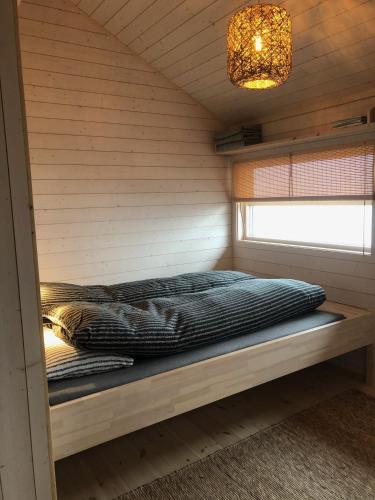 a bed in a cabin with a window and a chandelier at Hytte på Sørbølfjellet in Flå