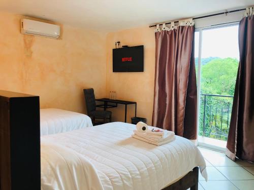 a hotel room with two beds and a window at Hotel Camino Surreal Xilitla in Xilitla