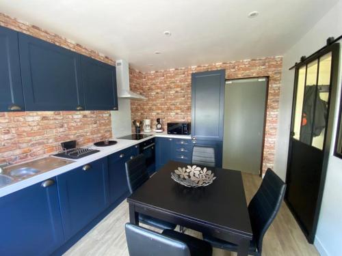 une cuisine avec des armoires bleues et une table noire dans l'établissement La petite cour, à Crécy-en-Ponthieu