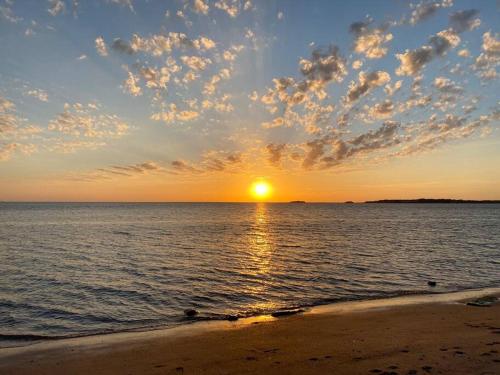 a sunset on the beach with the sun setting at Tiny house sur terrain boisé à 10 mn de la mer in Férel