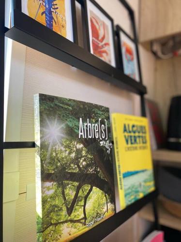 a book shelf with books on it next to a window at Tiny house sur terrain boisé à 10 mn de la mer in Férel