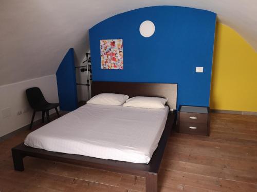 una camera con un letto con una parete blu e gialla di Mikhael Apartment a Monte SantʼAngelo