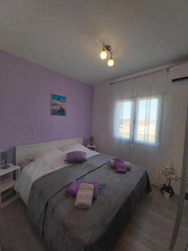 ein Schlafzimmer mit einem großen Bett mit lila Kissen in der Unterkunft Kuća za odmor Lazarić in Marčana