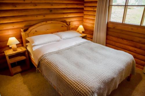 1 dormitorio con 1 cama en una cabaña de madera en Bynack, en Aviemore
