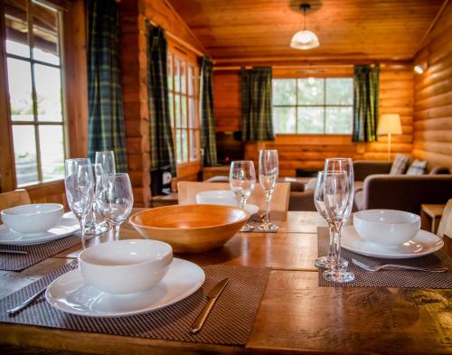 a wooden table with plates and glasses on it at Bynack in Aviemore