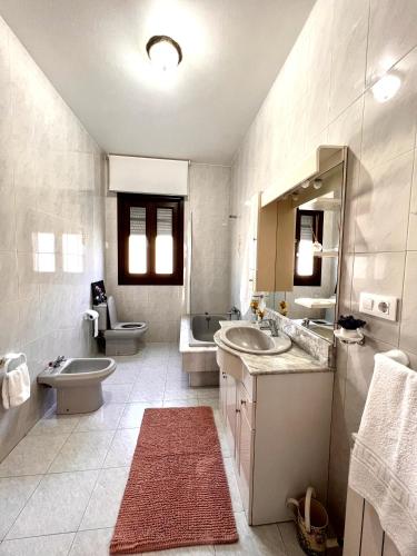 a bathroom with two sinks and a toilet and a tub at Descanso Natural Bueu in Bueu