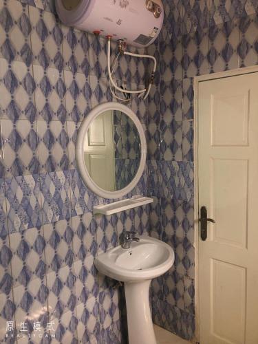 a bathroom with a sink and a mirror at AwaMuuLamin MANNEH GUEST HOUSE in Abuko
