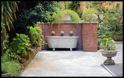 a bath tub sitting in a garden next to a brick wall at Liliumhotel in Rome